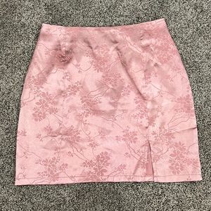pink silk mini skirt with flower detailing and zipper on the back and a slit